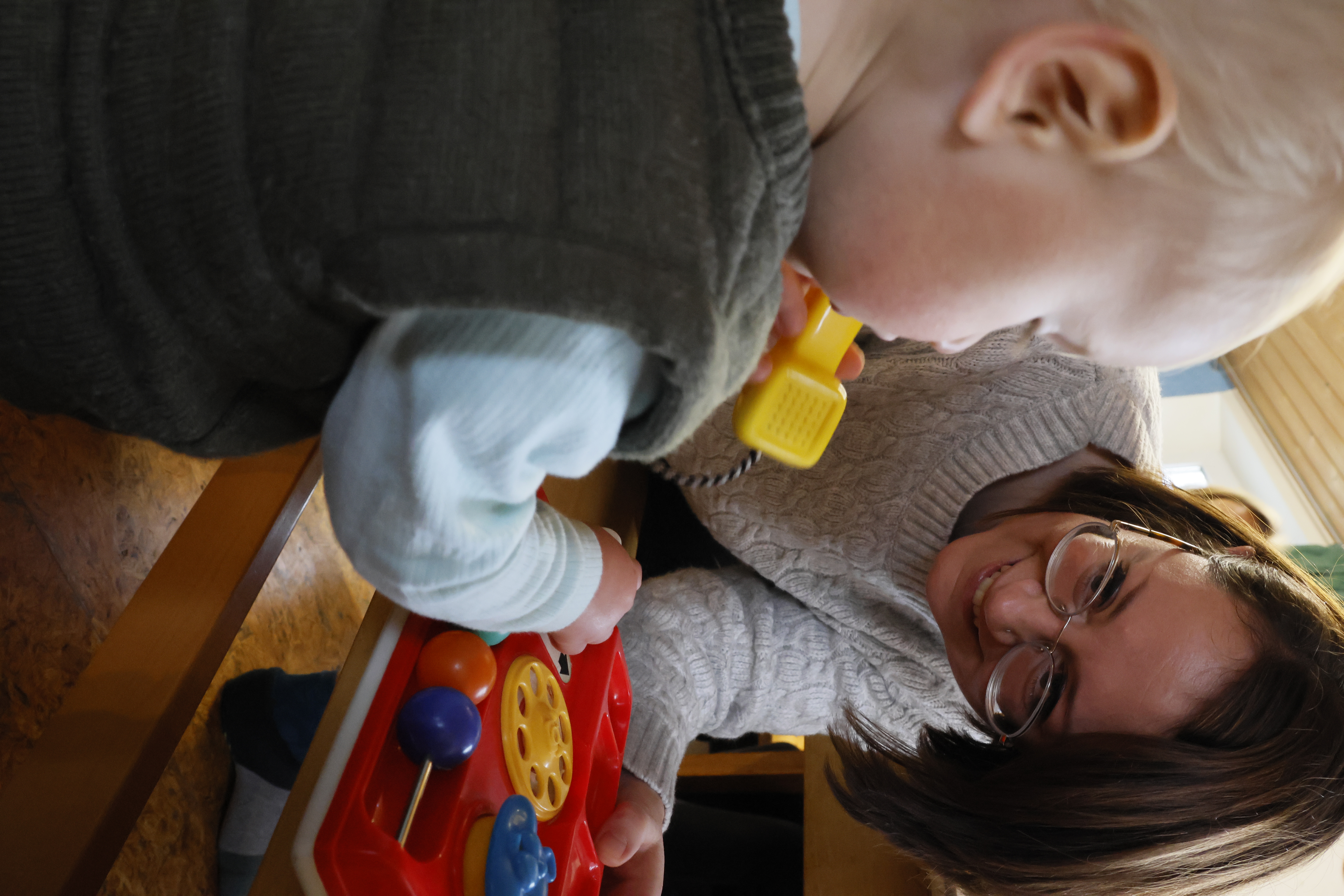 Lisa Fäustle, eine der Leiterinnen des Elterncafés Ottobeuren, spielt mit einem Kleinkind an einem Spiel-Telefon. 